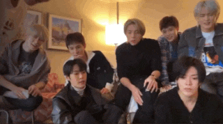 a group of young men are sitting on a couch in a living room .