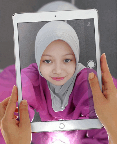 a person is holding a tablet with a picture of a girl in a hijab on it
