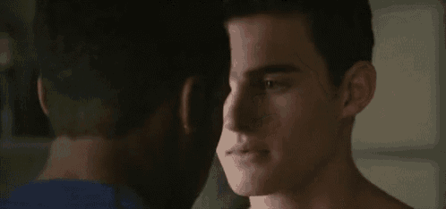 a close up of two men 's faces looking at each other in a dark room .