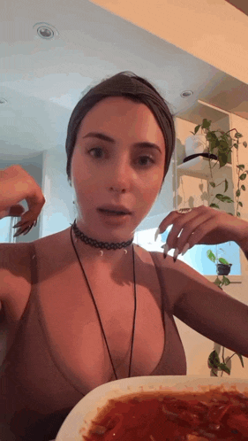 a woman wearing a choker and a necklace is eating a plate of food
