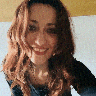 a woman with red hair is smiling and wearing a blue shirt