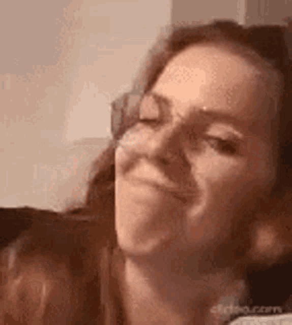 a close up of a woman making a funny face while wearing glasses .