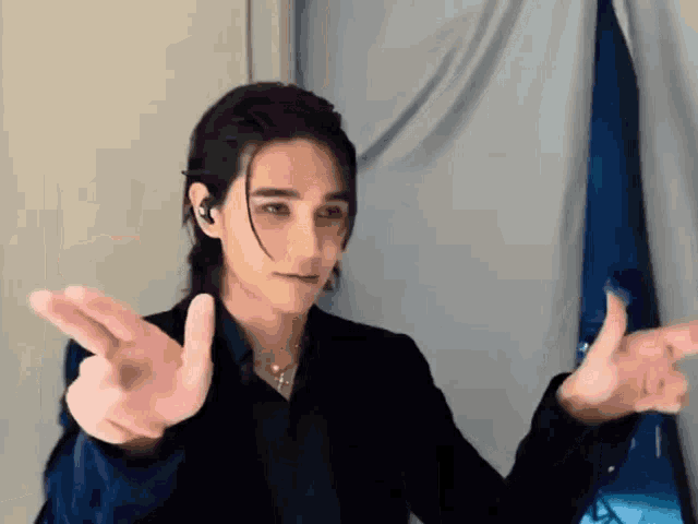 a man with long hair is making a peace sign with his fingers