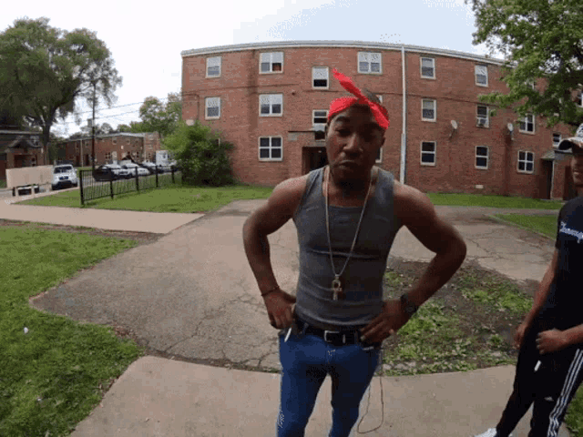 a man with a bandana on his head is standing in front of a building