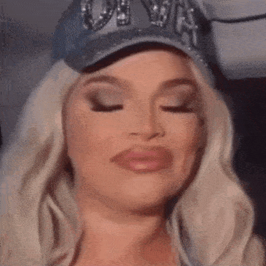 a close up of a woman wearing a baseball cap and making a funny face .