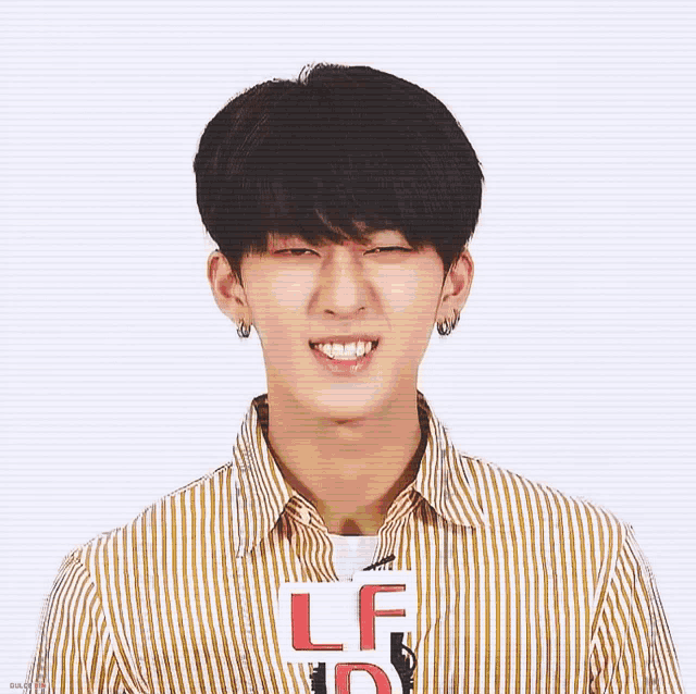 a young man wearing a yellow and white striped shirt is smiling and holding a sign that says lf