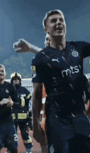 a soccer player wearing a mts jersey celebrates