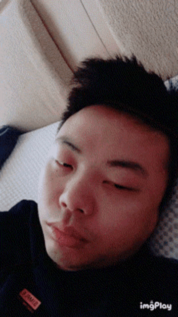 a man laying on a bed with his eyes closed and a label on his shirt that says ' i am a '