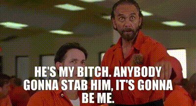 a man in an orange jumpsuit is standing next to another man in an orange jumpsuit and talking to him .
