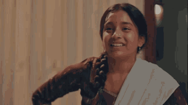 a woman with a braided hair and a nose ring is smiling .