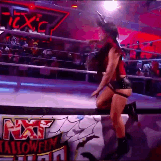 a woman in a bunny costume is jumping over a rope in a wrestling ring