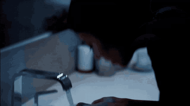 a person washing their face in a bathroom sink at night