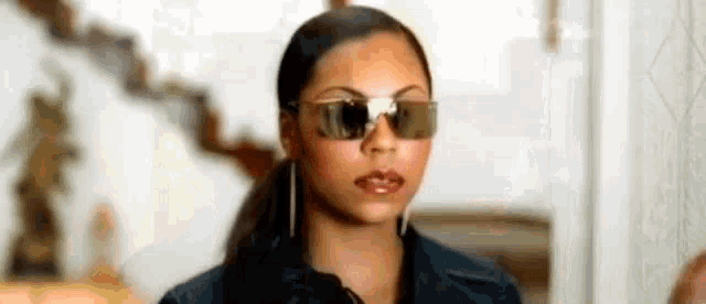 a woman wearing sunglasses and earrings is standing in front of a door .
