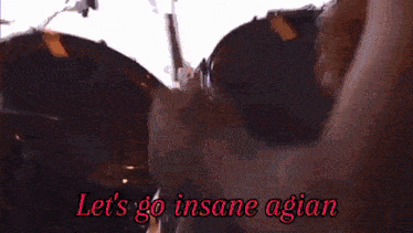 a man singing into a microphone while playing a guitar with the words " let 's go insane agian " written below