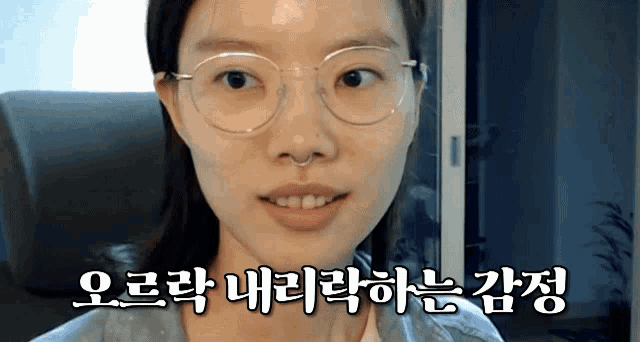 a woman wearing glasses and a nose ring is smiling in a video in korean