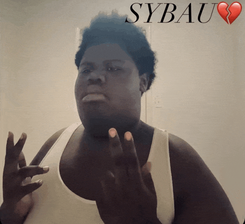 a man in a white tank top is standing in front of a poster that says sybau