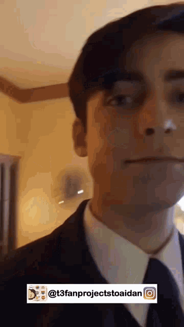 a young man in a suit and tie is looking at the camera .