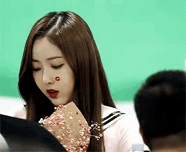 a girl with a red heart on her face is holding a piece of paper