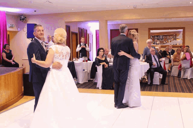 a bride and groom dance in front of a sign that says caledoni