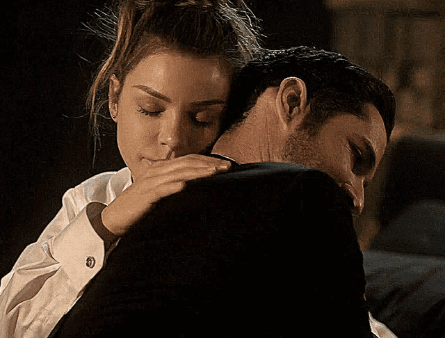a woman is hugging a man in a suit