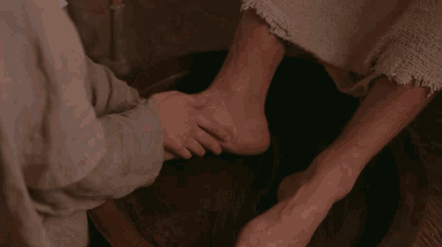 a person washing another person 's feet in a bucket
