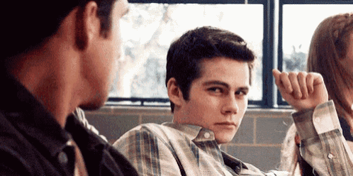 a man in a plaid shirt is sitting next to a woman in a room with other people .