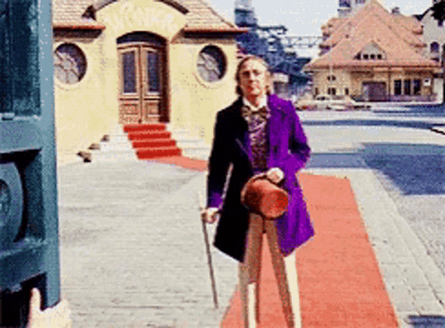 a man in a purple coat and top hat is standing in front of a building that says wonka