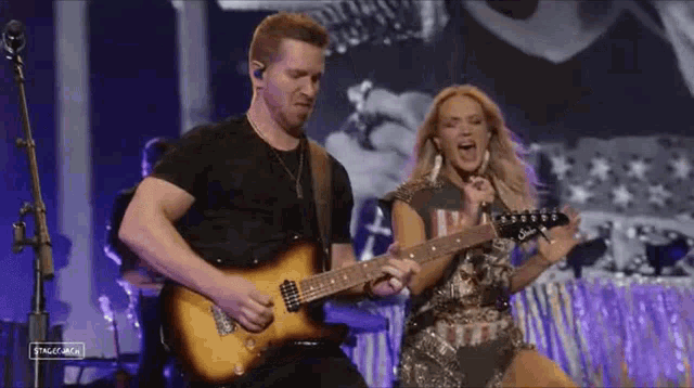 a man is playing a guitar next to a woman who is singing into a microphone .