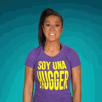 a woman in a purple shirt that says soy una hugger flexes her muscles