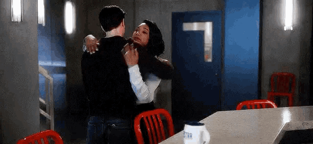 a man and a woman are hugging in a room .
