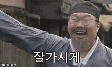 a man with glasses and a beard is laughing with his arms outstretched in korean .