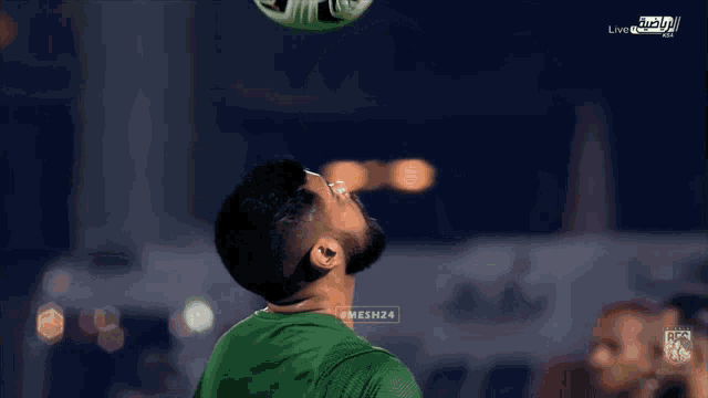 a man in a green shirt is juggling a soccer ball in front of a fox sports logo