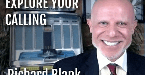 a man in a suit and tie is smiling in front of a jukebox and says `` explore your calling '' .