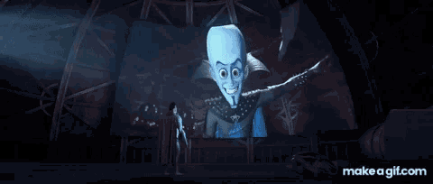 a man in a cape is standing in front of a large screen with a picture of megamind on it .