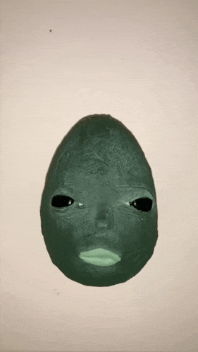 a green egg with a face on it is on a white background .