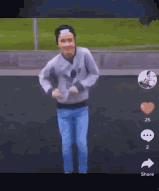 a man in a grey adidas sweatshirt and blue jeans is dancing on a field .