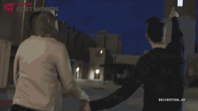 a man and woman are holding hands in front of a building that says fort worth