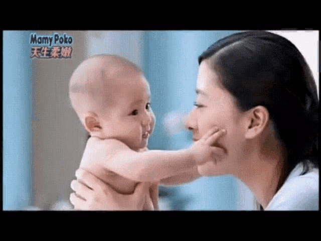 a woman is holding a baby in her arms and the baby is looking at the camera .