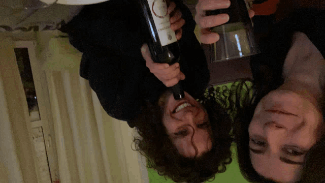 a man and a woman are holding a bottle of wine that says ' rosso ' on the label