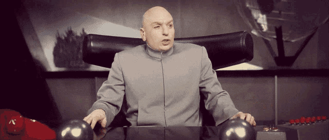 a bald man is sitting at a desk in a chair