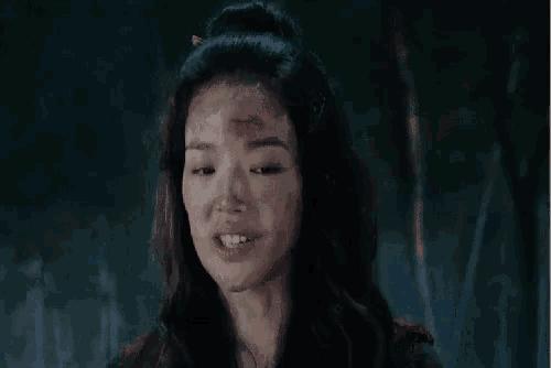a close up of a woman 's face with blood on her forehead .