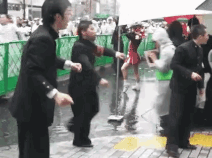 a group of people in suits are dancing in the rain on a street .