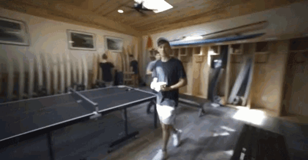 a man walking in a room with a ping pong table in the background