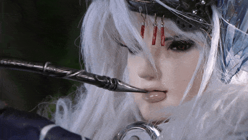 a close up of a doll with white hair and a sword in her mouth