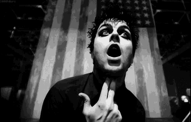 a black and white photo of a man making a funny face with his mouth open .