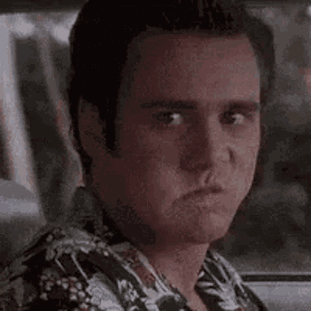 a man in a hawaiian shirt is sitting in the back seat of a car .