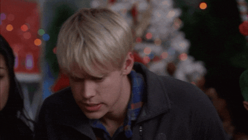 a man and a woman are looking at each other with christmas lights in the background