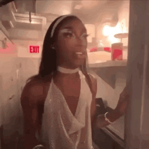 a woman in a white dress is standing in front of a refrigerator door .