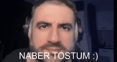 a man with a beard is wearing headphones and has the words naber tostum written on his face .
