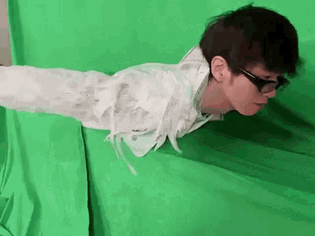 a man is laying on his back on a green screen .